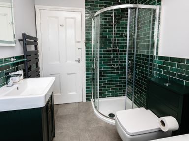 A bathroom with a shower enclosure sink toilet and storage cabinet at Old Coastguard Cottages Amble