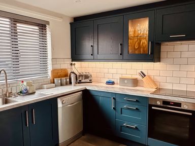 A kitchen with cabinets and appliances at Old Coastguard Cottages Amble