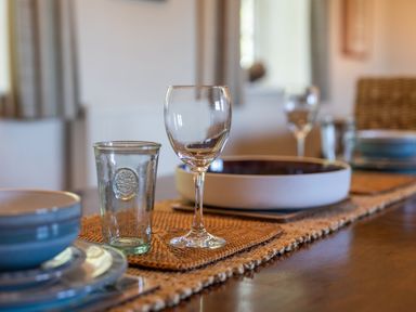 A dining table with glassware and dishware at Plumtree Cottage in Alnmouth
