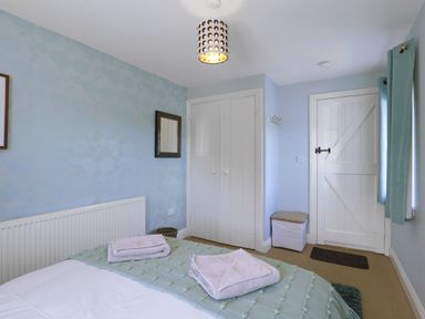 A bedroom with bed and towels at Plumtree Cottage in Alnmouth