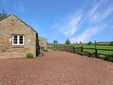 An outdoor area with a stone cottage and gravel driveway at Plumtree Cottage in Alnmouth