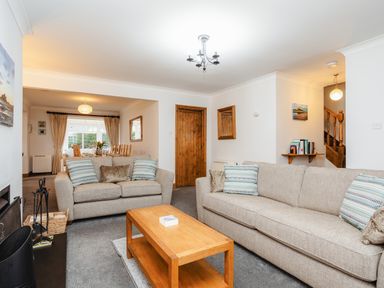 A living room with sofas and a wooden coffee table next to a dining area with a table and chairs at Armstrong Cottages No30 in Bamburgh