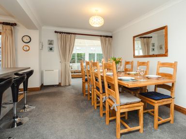 A dining room with wooden table and chairs set with plates and glasses at Armstrong Cottages No30 Bamburgh