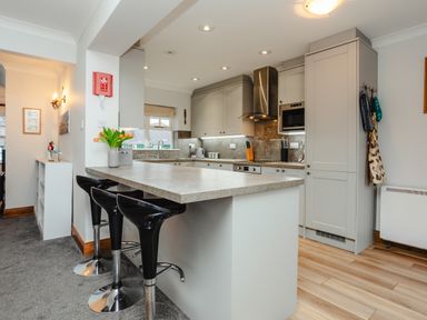 A kitchen with an island countertop and three black bar stools at Armstrong Cottages No30 in Bamburgh