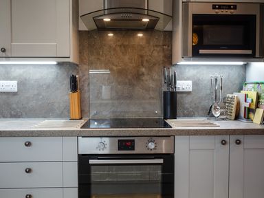 A kitchen with electric oven and stove knives in blocks cooking utensils and a microwave at Armstrong Cottages No30 Bamburgh