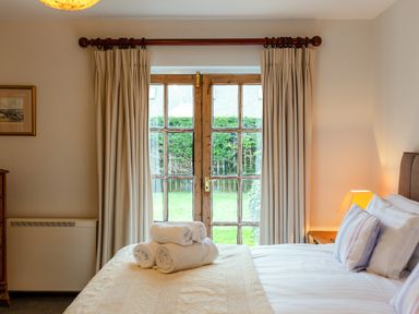 A bedroom with a bed with folded towels on it next to a window with curtains at Armstrong Cottages No30 in Bamburgh