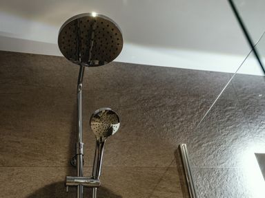 A showerhead and handheld shower on a tiled wall at Armstrong Cottages No30 in Bamburgh