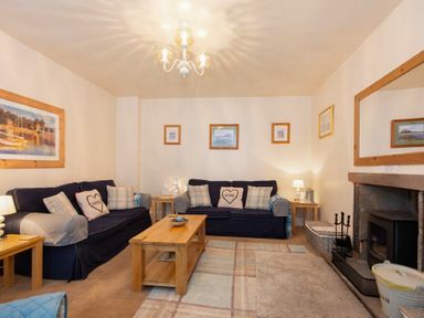 A living room with two sofas a coffee table a fireplace and wall art at Lobster Pot Cottage in Seahouses