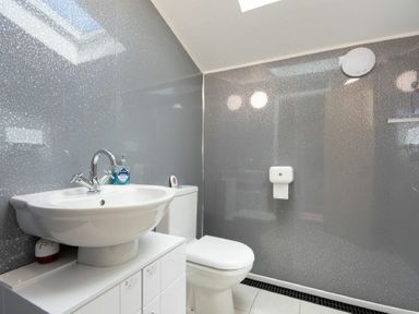 A bathroom with a white sink, a toilet, and a wall-mounted toilet paper holder at Lobster Pot Cottage in Seahouses