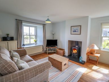 A living room with a sofa a TV a fireplace and wooden furniture at Beachward in Embleton