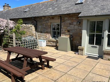 An outdoor area with a wooden table and benches at Beachward in Embleton