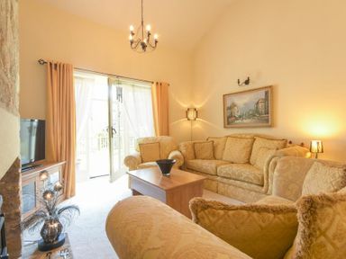 A living room with sofas a coffee table a television and a painting at Lavender Cottage Village Farm in Seahouses