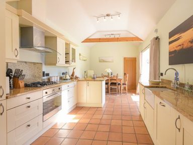 A kitchen with countertops cabinets a gas stove oven a dining table and chairs at Lavender Cottage Village Farm in Seahouses