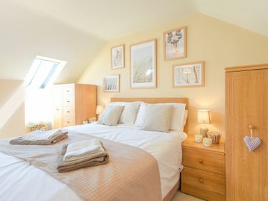 A bedroom with a double bed bedside tables lamps and wall art at Lavender Cottage Village Farm in Seahouses