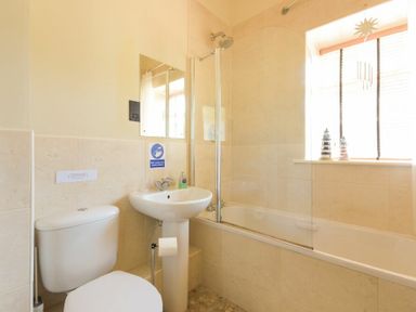 A bathroom with a toilet sink and bathtub with a shower at Lavender Cottage Village Farm in Seahouses