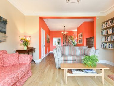 A living room with sofas a wooden coffee table flowers and bookshelves at Estuary View in Alnmouth