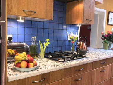 A kitchen counter with fruit bowl kettle stove and flowers at Estuary View in Alnmouth