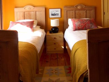 A bedroom with two single wooden beds and a wooden nightstand with a lamp between them at Estuary View in Alnmouth