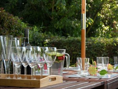 A wooden outdoor table with empty wine glasses and a pitcher of fruit water at Estuary View in Alnmouth