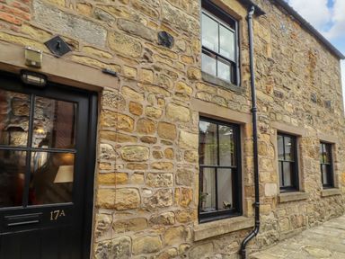 An exterior wall of a stone house with windows and a door at Lavender Cottage (Bailiffgate) Alnwick