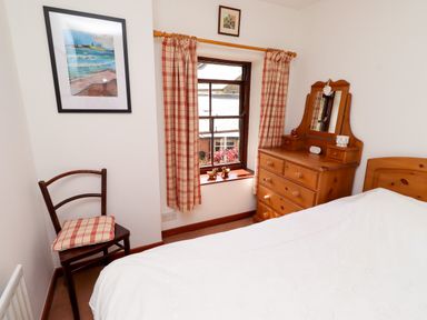 A bedroom with a bed and dresser at Lavender Cottage (Bailiffgate) Alnwick