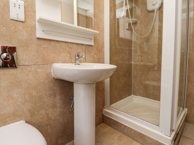 A bathroom with a pedestal sink a glass-enclosed shower and a toilet at Kittling Cottage in Bamburgh