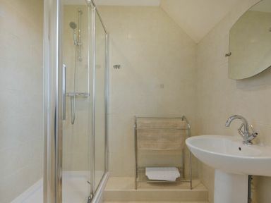 A bathroom with a shower enclosure a towel rack and a sink with a mirror at Smithy Court in Craster