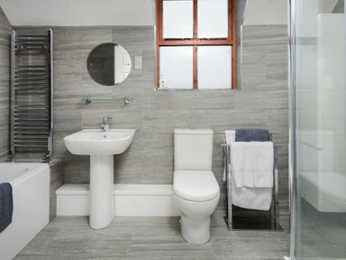 A bathroom with a toilet sink towel rack bathtub and shower at Smithy Court in Craster