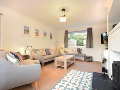 A living room with two sofas an armchair a coffee table a fireplace and a window with curtains at Barmoor in Embleton