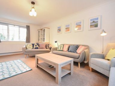 A living room with two sofas a coffee table an armchair a rug and framed pictures on the wall at Barmoor in Embleton