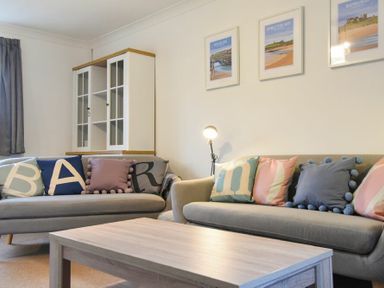 A living room with two sofas with cushions and a wooden coffee table at Barmoor in Embleton