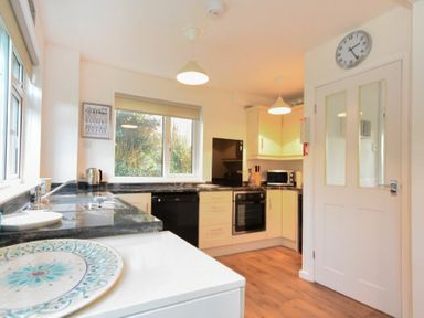 A kitchen with countertops dishwasher oven microwave and a clock on a door at Barmoor in Embleton