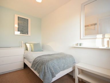 A bedroom with a single bed a dresser a mirror and a bench at Barmoor in Embleton
