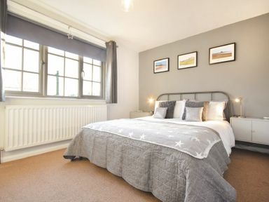 A bedroom with a double bed grey bedding bedside tables lamps and framed pictures on the wall at Barmoor in Embleton