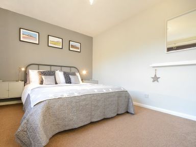 A bedroom with a double bed and framed pictures on the wall at Barmoor in Embleton