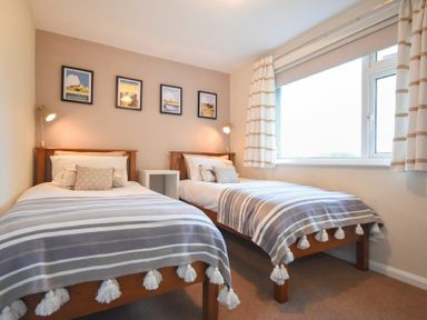 A bedroom with two single beds bedside table lamps framed pictures on wall at Barmoor in Embleton