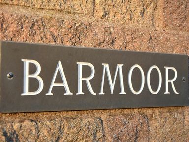 A black rectangular sign with the word BARMoor on a brick wall at Barmoor Embleton