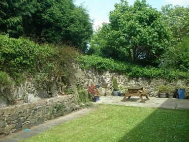 A garden with a stone wall wooden picnic table potted plants and green grass at Barmoor in Embleton