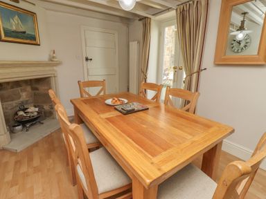 A dining room with a wooden table and chairs at Marie's Cottage in Craster