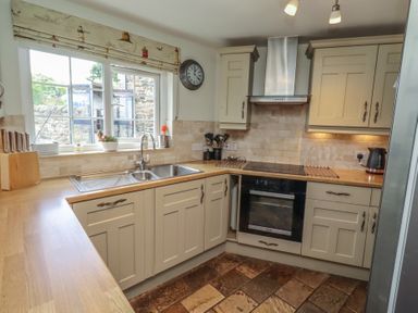 A kitchen with cabinets, sink, and appliances at Marie's Cottage in Craster