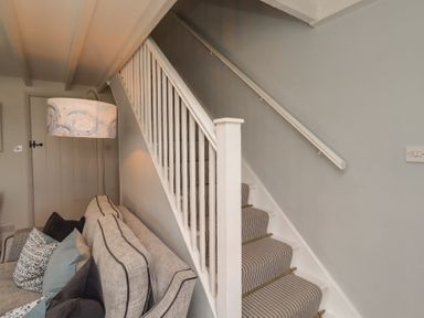 A staircase leading to the upper floor from the living room at Marie's Cottage in Craster