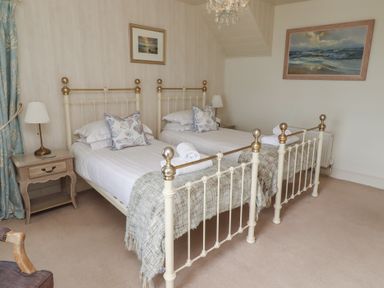 A bedroom with two beds and a nightstand at Marie's Cottage in Craster