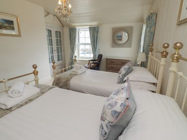 A bedroom with twin beds and a dresser at Marie's Cottage in Craster