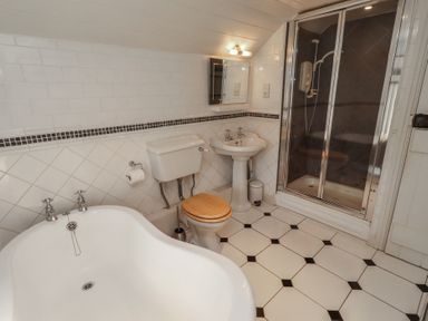 A bathroom with a bathtub, toilet, sink, and shower at Marie's Cottage in Craster
