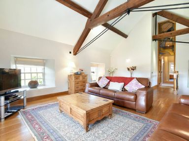 A living room with leather sofas wooden coffee table wooden chest of drawers and exposed ceiling beams at Budle Sands in Bamburgh
