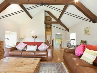 A living room with brown leather sofas wooden coffee table exposed wooden beams and a rug at Budle Sands in Bamburgh