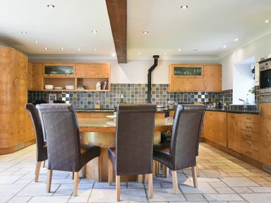A kitchen with a round wooden table and six brown leather chairs at Budle Sands in Bamburgh