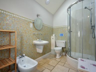 A bathroom with a shower cubicle toilet sink bidet and wooden shelving unit at Budle Sands in Bamburgh