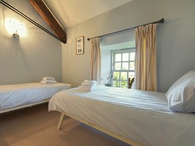 A bedroom with two single beds and a window with curtains at Budle Sands in Bamburgh