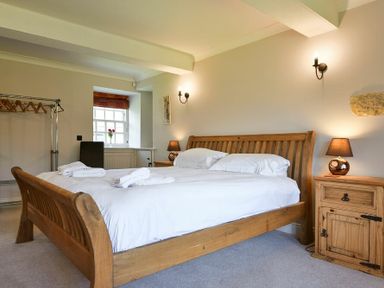 A bedroom with a wooden bed frame and bedside table with lamp at Budle Sands in Bamburgh